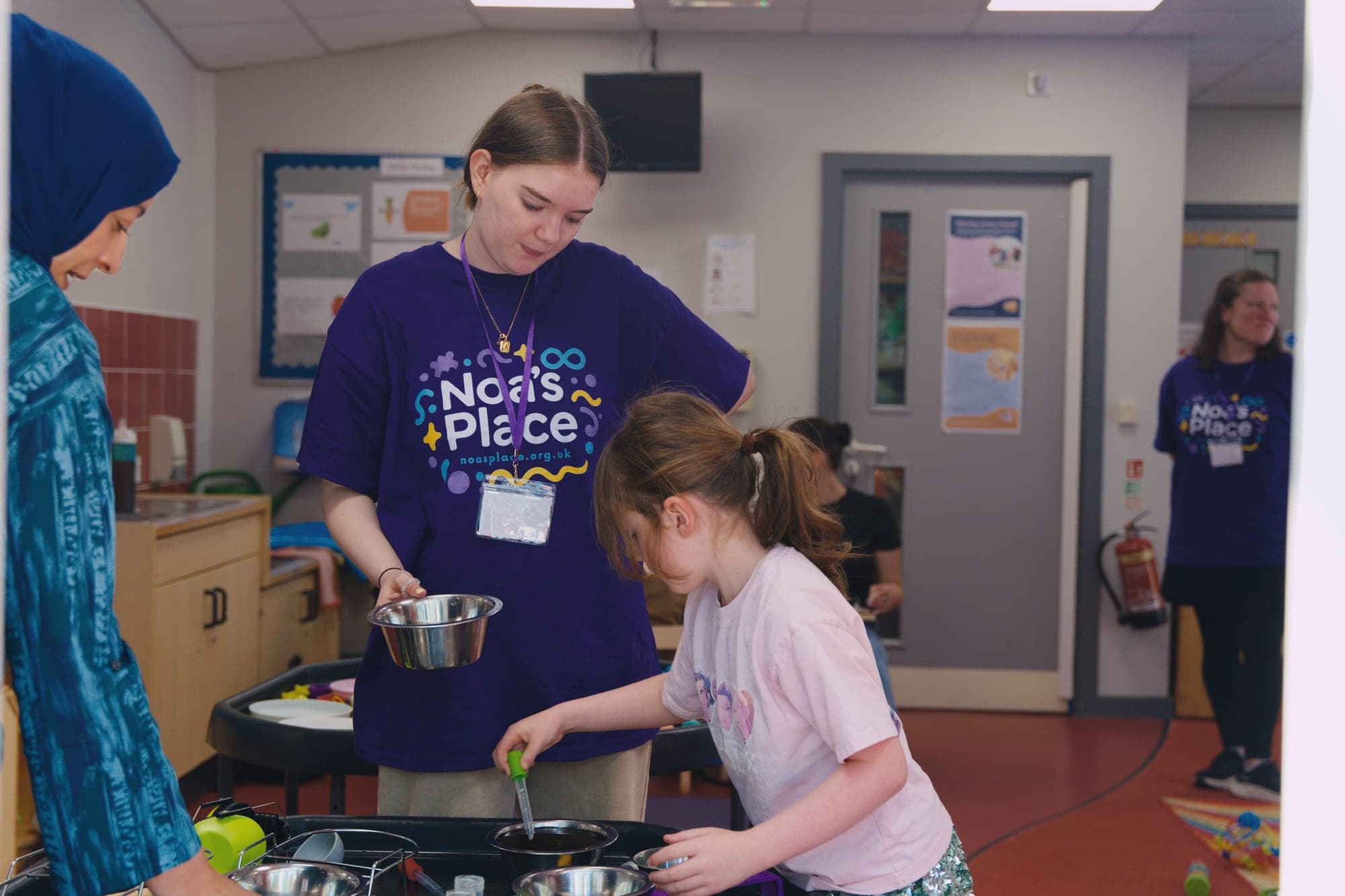 A Noa's Place team member supporting a child during sensory water play