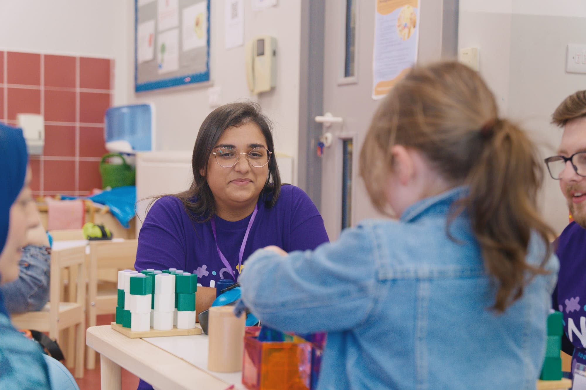 A team member supporting a child with stacking toys